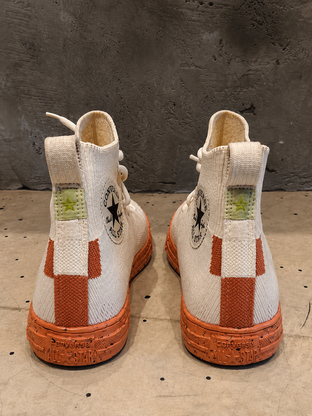 Pair of beige and brown high-top sneakers with a checkered pattern on a textured surface.