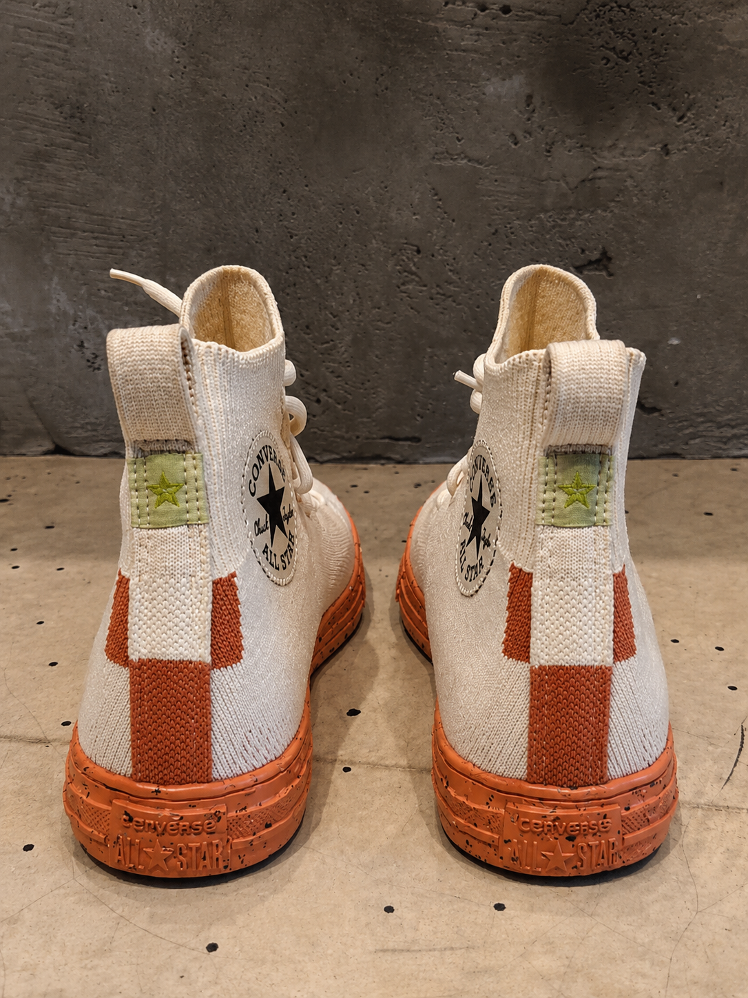 Pair of beige and brown high-top sneakers with a checkered pattern on a textured surface.