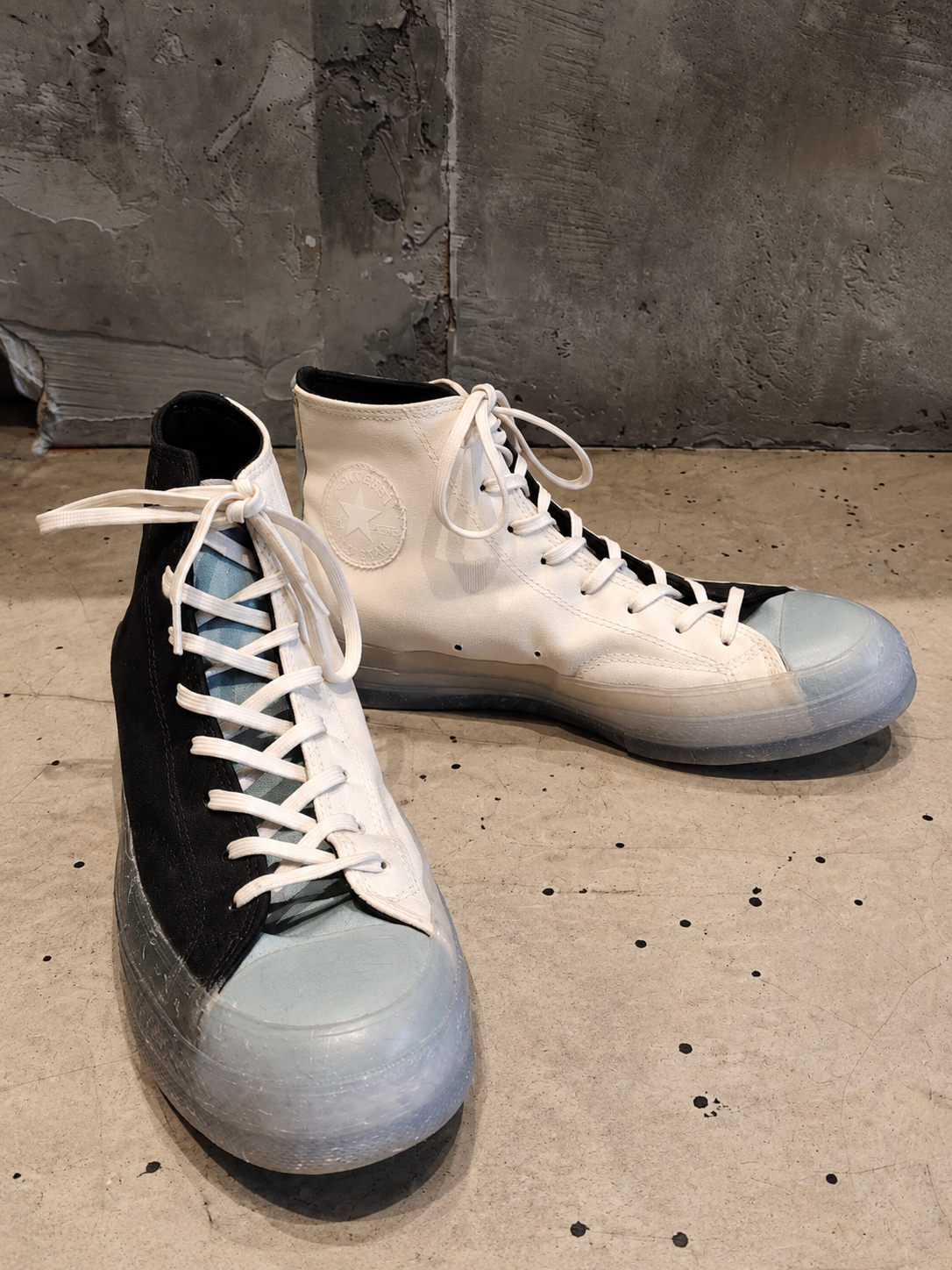 Pair of high-top sneakers with black and light blue design on a concrete floor.