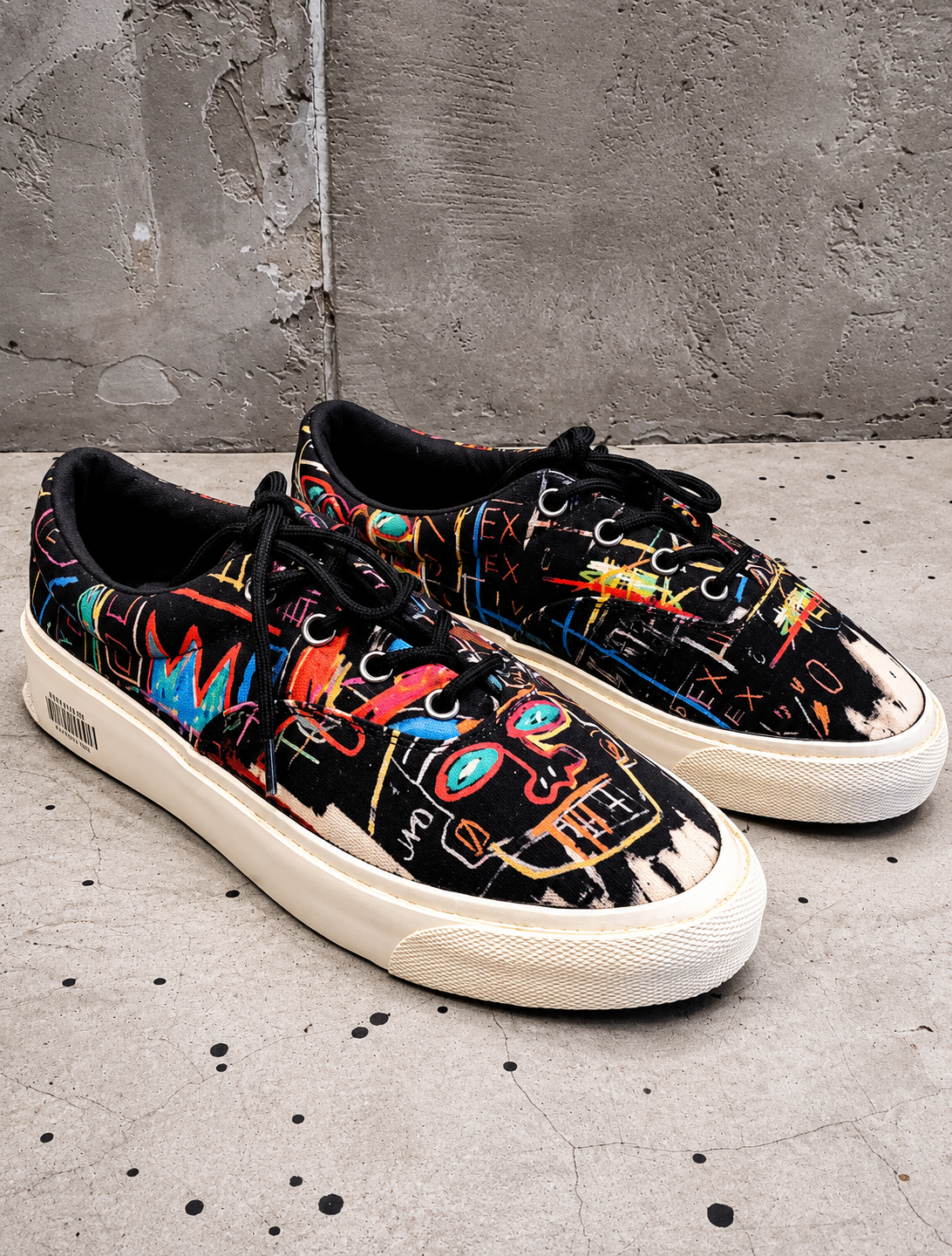 Colorful sneakers with abstract designs on a concrete floor.