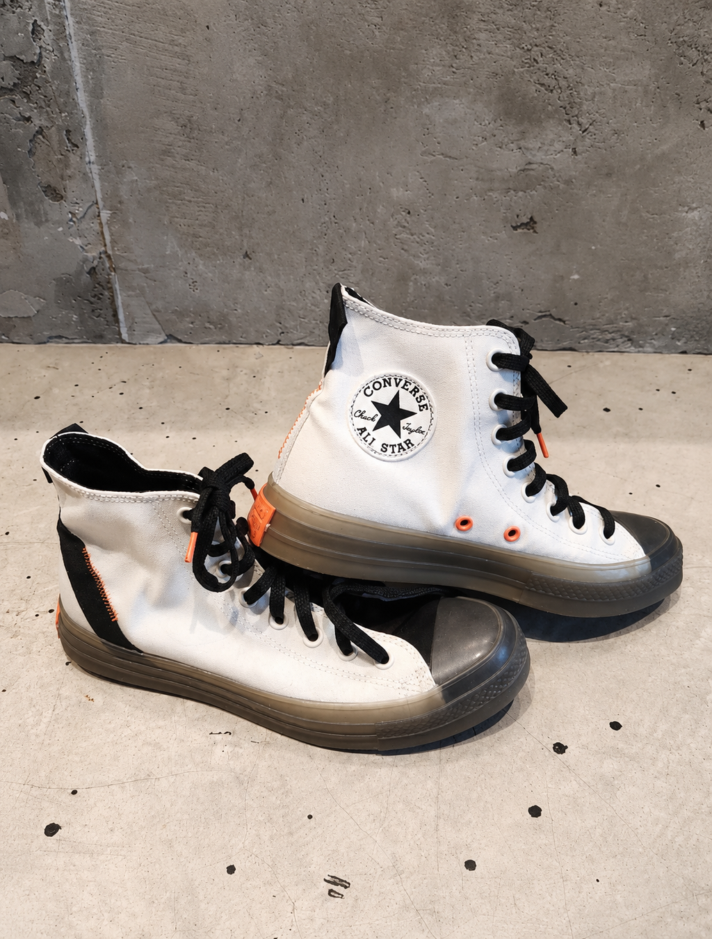 White high-top sneakers with black accents on a concrete floor.